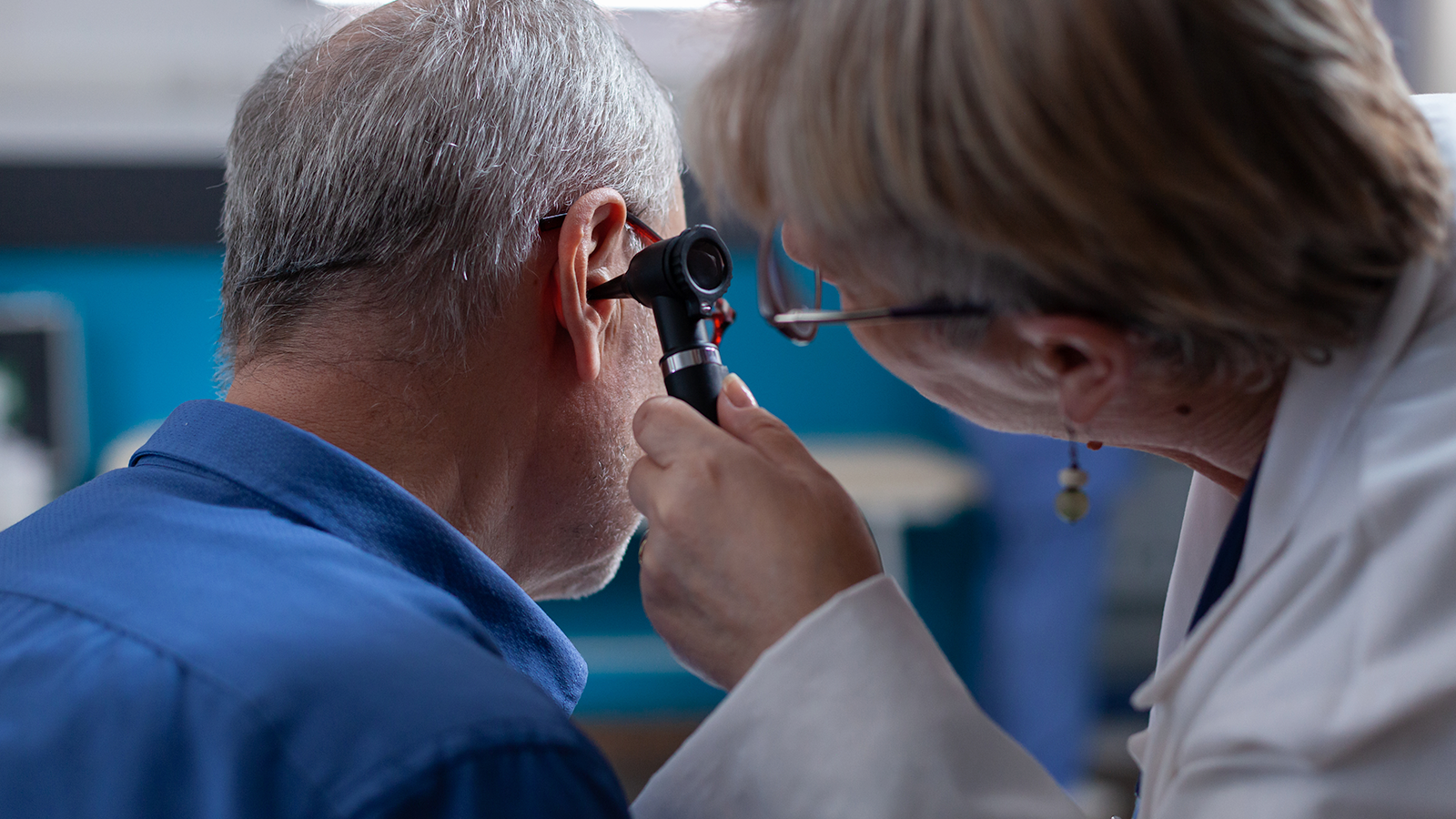 A registered audiologist checking a patient’s ear